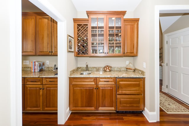 bar with light stone countertops, sink, and dark hardwood / wood-style flooring