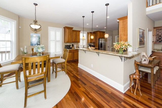 kitchen with kitchen peninsula, stainless steel fridge, a healthy amount of sunlight, and dark hardwood / wood-style flooring