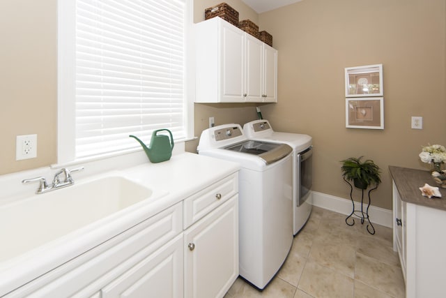 clothes washing area with light tile patterned floors, sink, separate washer and dryer, and cabinets