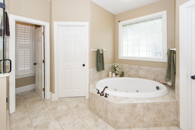 bathroom with a relaxing tiled tub and tile patterned floors