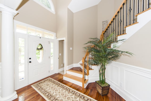 entryway with hardwood / wood-style floors, a high ceiling, a healthy amount of sunlight, and decorative columns