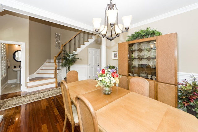 dining room with sink, crown molding, an inviting chandelier, and hardwood / wood-style floors