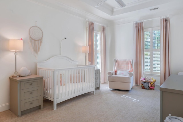 bedroom with light carpet, a nursery area, crown molding, and a raised ceiling