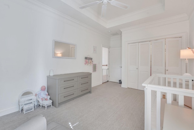 bedroom featuring light carpet, crown molding, a raised ceiling, baseboards, and a closet
