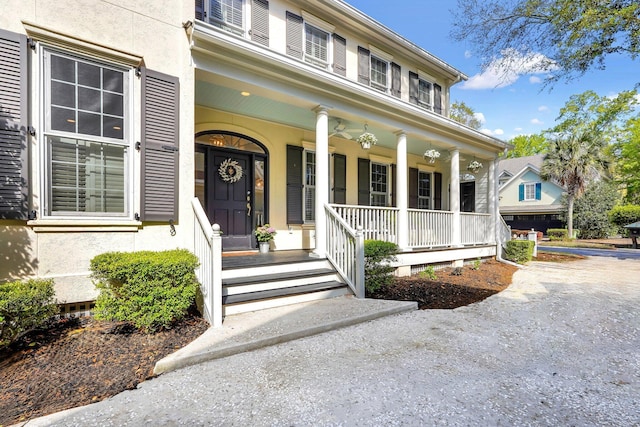view of exterior entry with covered porch and stucco siding