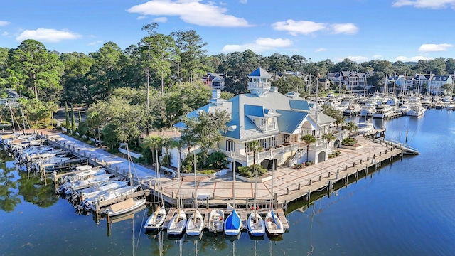aerial view of property and surrounding area featuring a nearby body of water, a marina, and a tree filled landscape