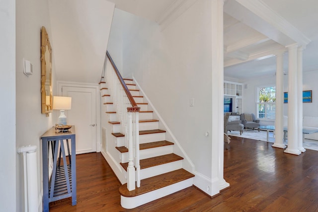 stairway featuring decorative columns, wood finished floors, beamed ceiling, and ornamental molding