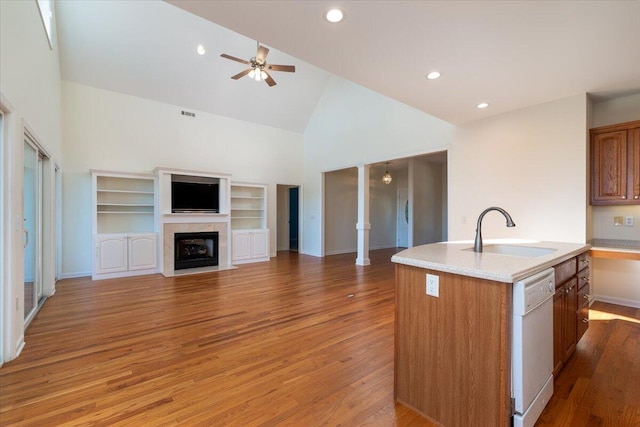 kitchen featuring sink, light hardwood / wood-style flooring, high vaulted ceiling, dishwasher, and an island with sink