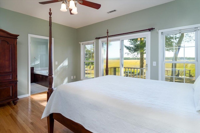 bedroom featuring connected bathroom, multiple windows, ceiling fan, and light hardwood / wood-style flooring