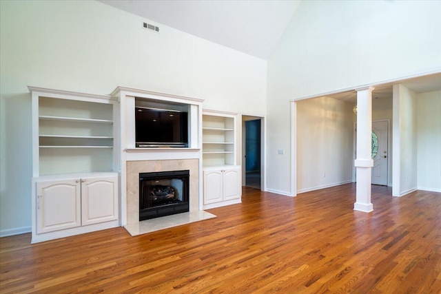 unfurnished living room with hardwood / wood-style flooring, built in shelves, and high vaulted ceiling