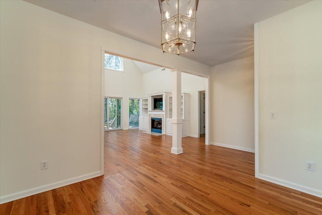 unfurnished living room with wood-type flooring and a notable chandelier