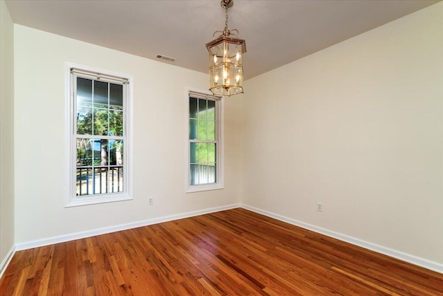 spare room featuring hardwood / wood-style floors and a chandelier