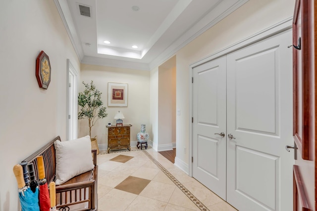 corridor featuring light tile patterned floors, a tray ceiling, and ornamental molding