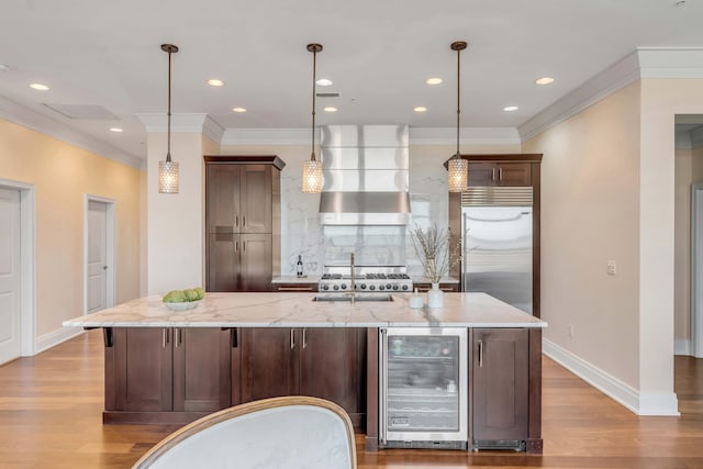 kitchen featuring decorative light fixtures, stainless steel built in refrigerator, wine cooler, light stone countertops, and a spacious island