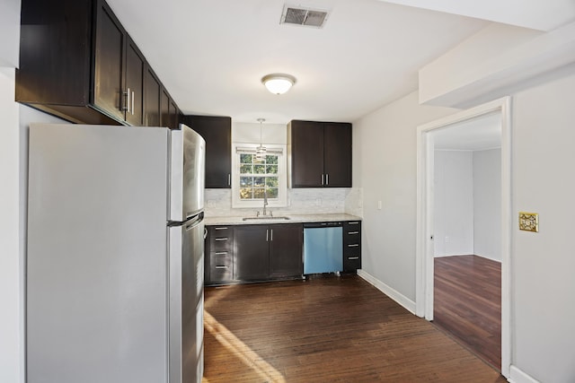 kitchen featuring dishwasher, sink, hanging light fixtures, white fridge, and dark brown cabinetry