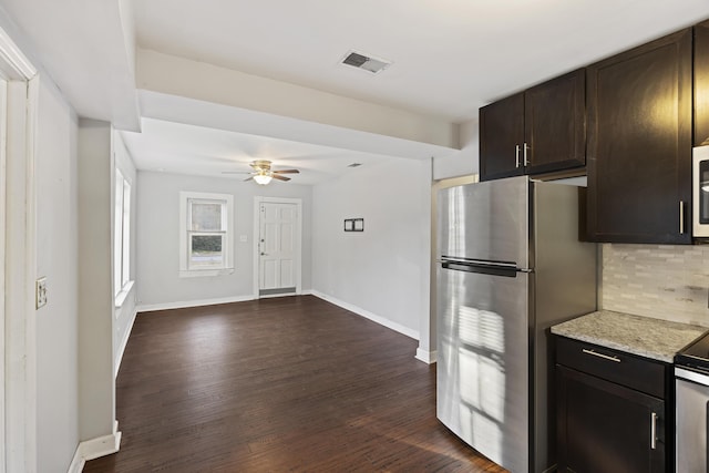 kitchen featuring dark brown cabinetry, ceiling fan, dark hardwood / wood-style floors, backsplash, and stainless steel fridge