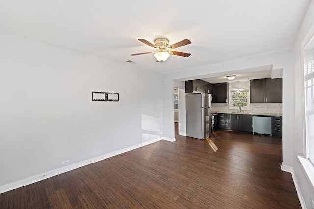 unfurnished living room with ceiling fan, dark wood-type flooring, and sink