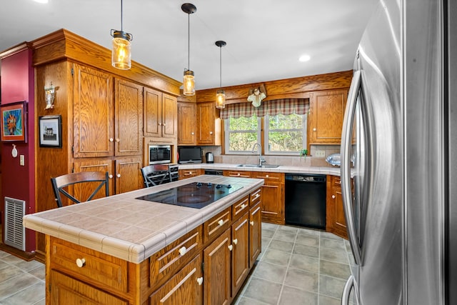 kitchen with sink, a kitchen island, black appliances, tile countertops, and decorative light fixtures