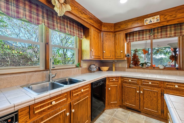 kitchen featuring tile counters, black dishwasher, sink, and plenty of natural light