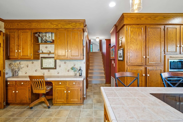 kitchen with light tile patterned flooring, tile countertops, and built in desk