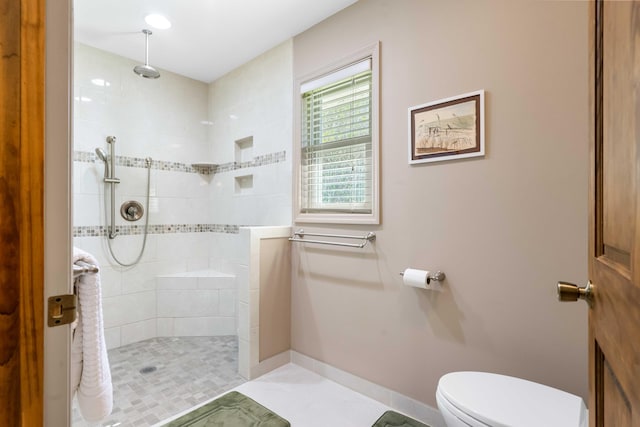 bathroom with toilet, tile patterned flooring, and a tile shower