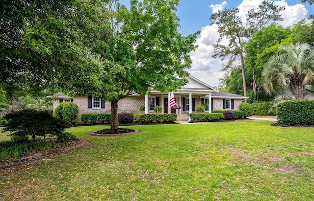 view of front facade with a front lawn, covered porch, and brick siding