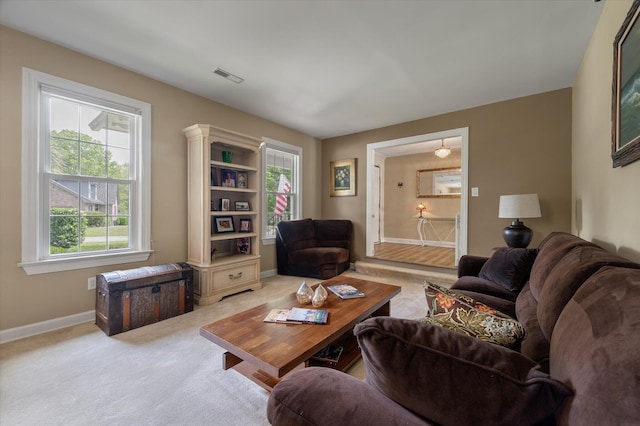carpeted living area with healthy amount of natural light and baseboards