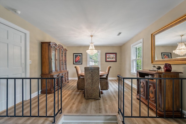 dining space with a chandelier, wood finished floors, and baseboards