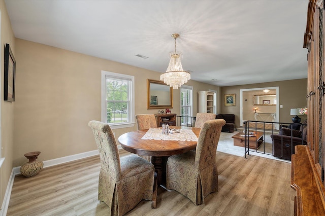 dining room featuring light wood-style floors, a chandelier, and baseboards