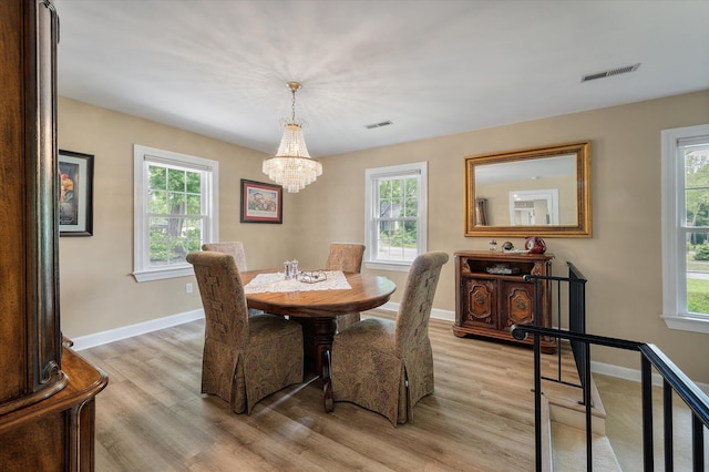 dining area featuring a chandelier, light wood-style floors, and baseboards