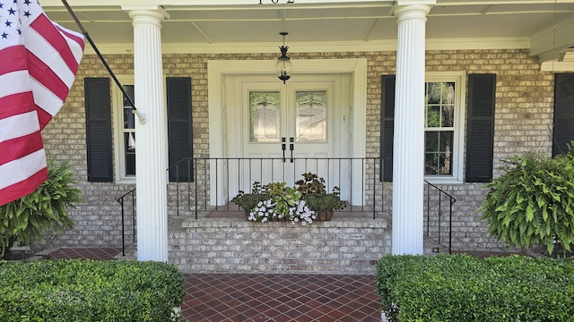 doorway to property with a porch and brick siding