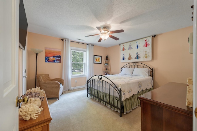 bedroom with light carpet, ceiling fan, and a textured ceiling