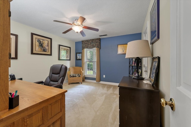 office space featuring a ceiling fan, light colored carpet, a textured ceiling, and baseboards