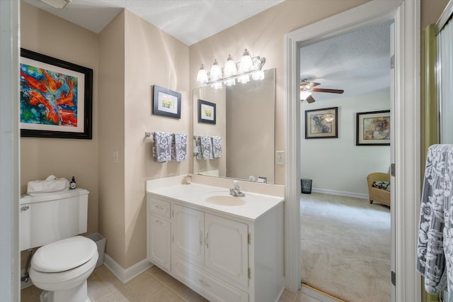 bathroom with a ceiling fan, toilet, baseboards, vanity, and a textured ceiling