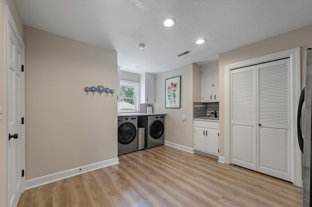 laundry room featuring independent washer and dryer, light wood-style floors, baseboards, a textured ceiling, and recessed lighting