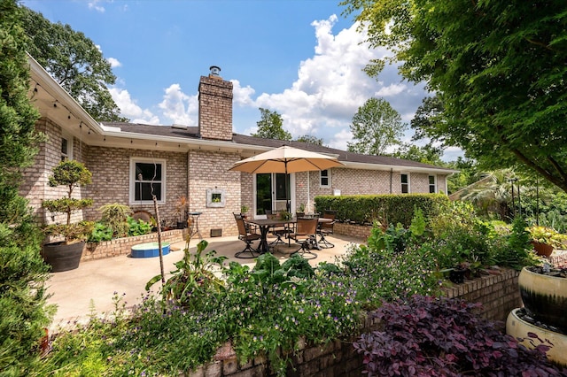rear view of property featuring a patio area, a chimney, and brick siding