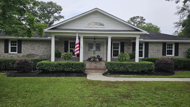 view of front of property with brick siding, a front yard, and a porch