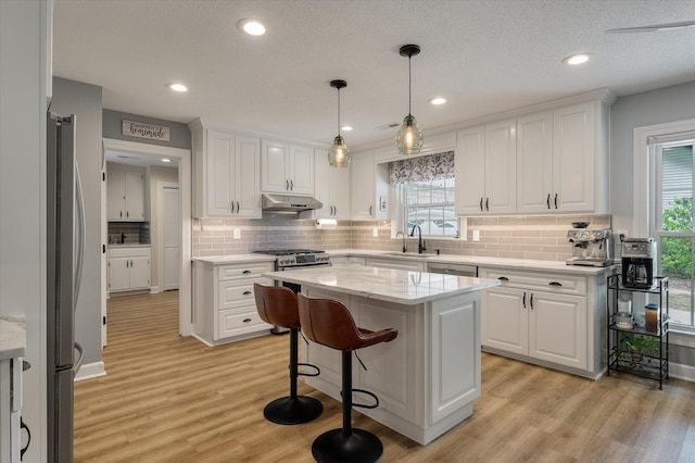 kitchen with a sink, white cabinets, light wood finished floors, and recessed lighting
