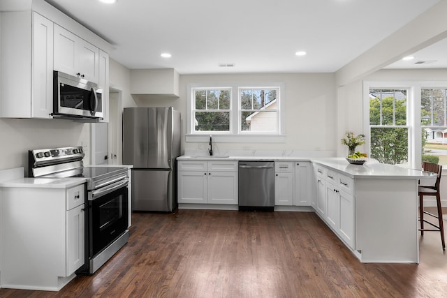 kitchen with stainless steel appliances, white cabinetry, sink, and kitchen peninsula