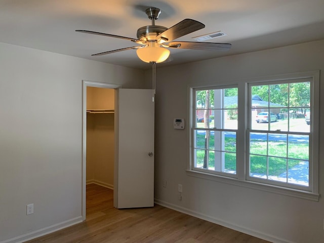 unfurnished bedroom with light wood-style flooring, visible vents, a spacious closet, and multiple windows