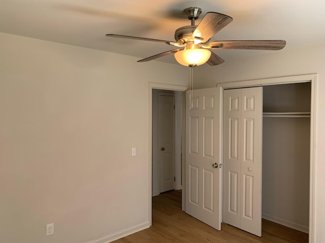 unfurnished bedroom featuring light wood finished floors, a closet, a ceiling fan, and baseboards