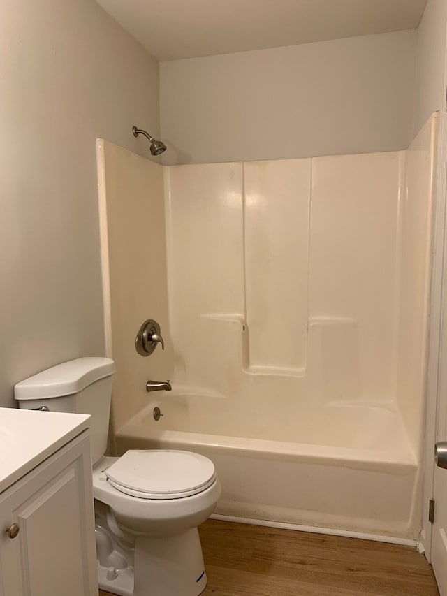 bathroom with toilet, bathtub / shower combination, wood finished floors, and vanity