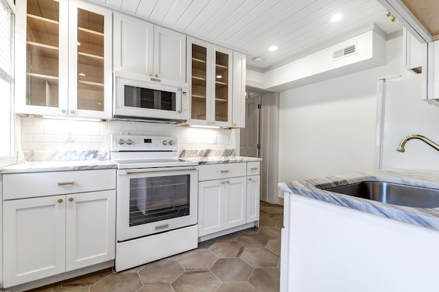 kitchen featuring backsplash, white appliances, tile flooring, white cabinets, and sink