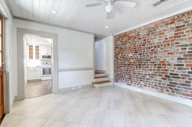 tiled spare room featuring brick wall and ceiling fan