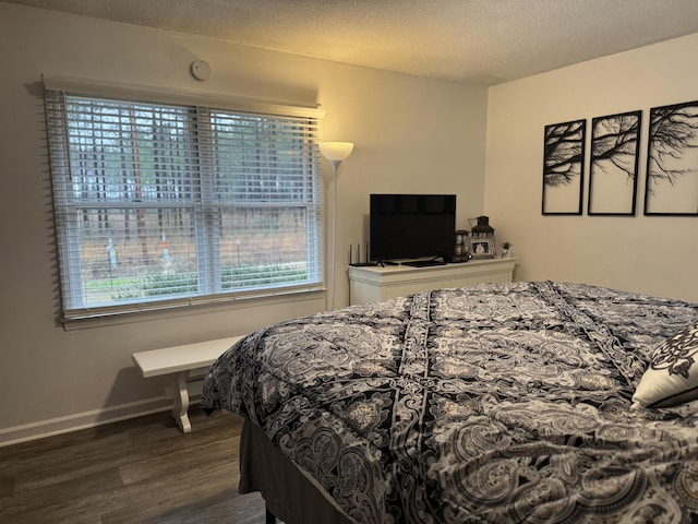 bedroom with baseboards, a textured ceiling, and wood finished floors