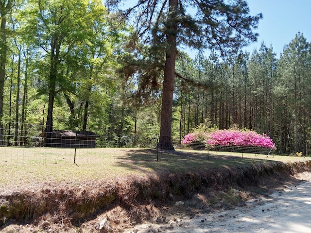 surrounding community featuring a forest view and fence