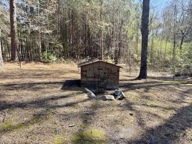 view of yard with an outbuilding, a wooded view, and a storage unit