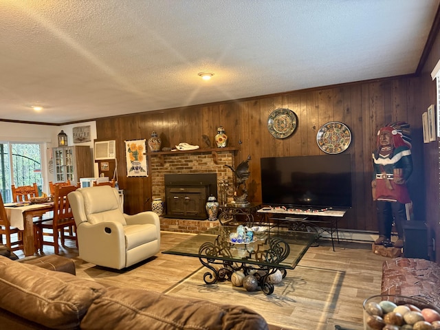 living room featuring wood finished floors, a fireplace, wood walls, a textured ceiling, and crown molding