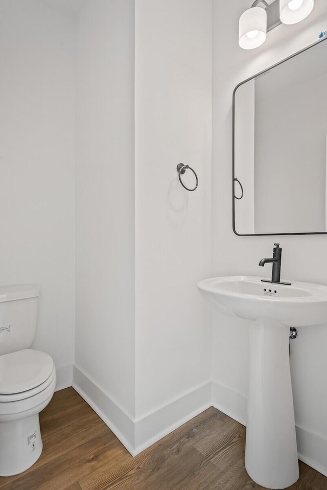 bathroom featuring toilet, baseboards, and wood finished floors