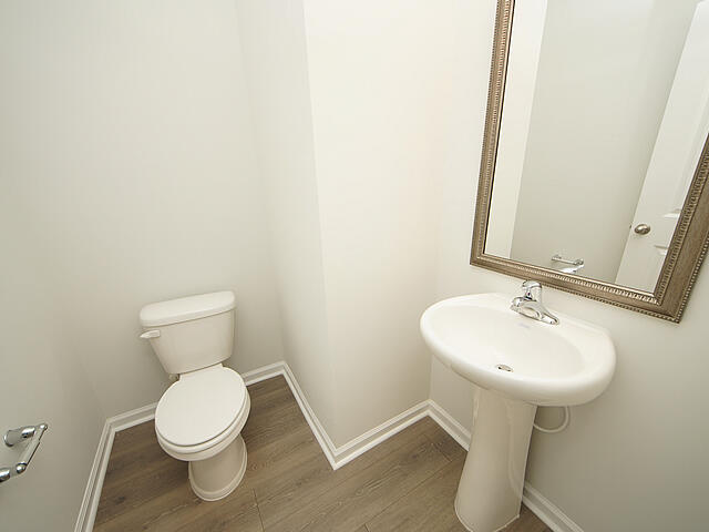 bathroom with baseboards, toilet, and wood finished floors